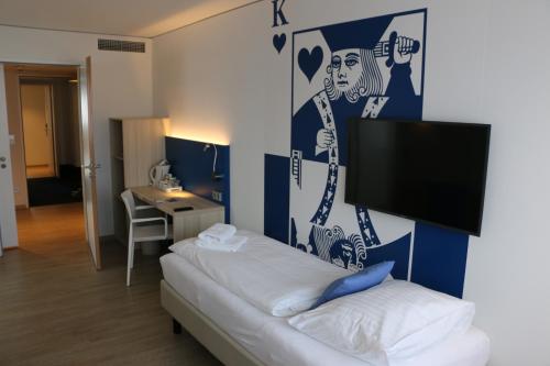 um quarto com uma cama e uma televisão na parede em IBB Hotel Paderborn em Paderborn