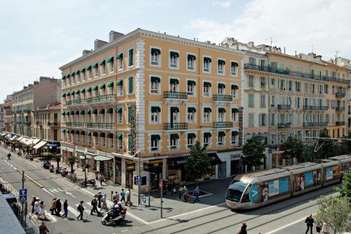 a train on a city street with a building at Hôtel Univers in Nice