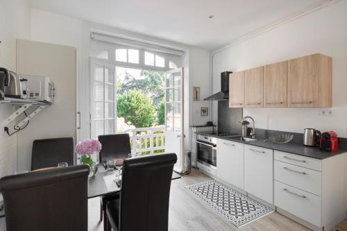 une cuisine avec des armoires blanches et une table avec des chaises dans l'établissement Le Safran by Cocoonr, à Dinard