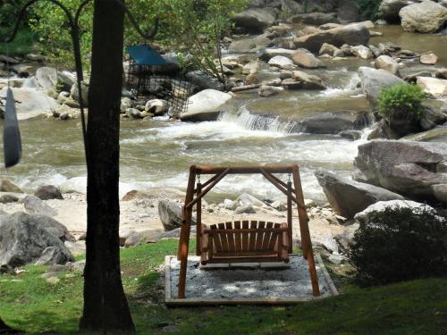 a bench sitting in front of a river at The Evening Shade River Lodge and Cabins in Chimney Rock