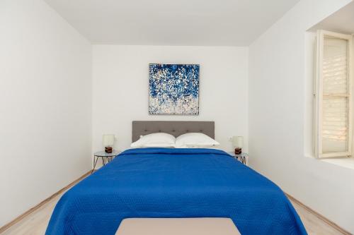 a white bedroom with a blue bed with two pillows at Dominium Old City Suite in Dubrovnik