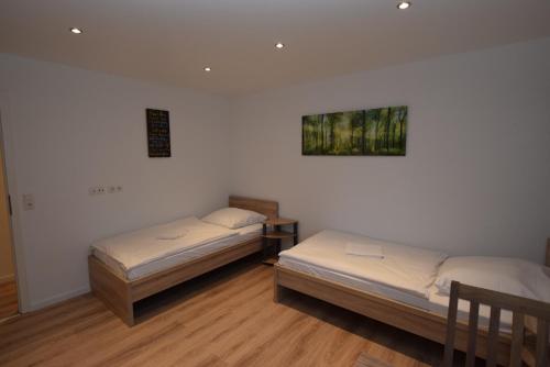 twee bedden in een kamer met witte muren en houten vloeren bij AB Apartment Objekt 109 in Ludwigsburg