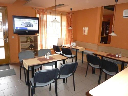 a restaurant with tables and chairs and a flat screen tv at Penzion Vis a Vis in Třebíč