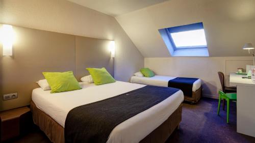 a hotel room with two beds and a table at Campanile Genève - Ferney-Voltaire in Ferney-Voltaire
