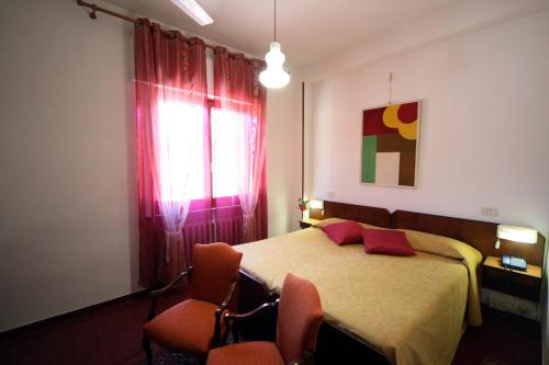 a bedroom with a bed with two chairs and a window at Albergo I Longobardi in Chiusi
