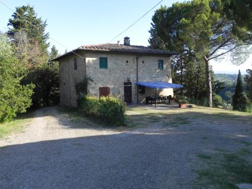 an old house with a blue awning in front of it at Agriturismo Le Ginestruzze in Montespertoli