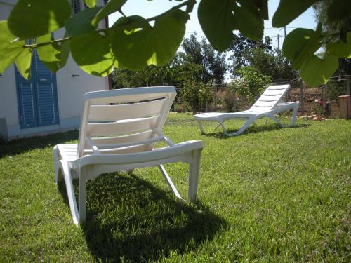 two white lawn chairs sitting in the grass at Casa vacanze La Meridiana in Donnalucata