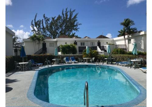 a swimming pool with tables and chairs in front of a house at Plum Tree Club in Bridgetown
