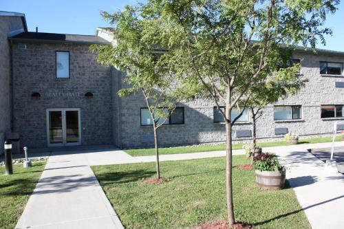 un edificio con un árbol delante de él en Residence & Conference Centre - Brockville, en Brockville