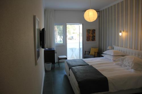 a hotel room with a large bed and a window at Hotel Vasco Da Gama in Monte Gordo