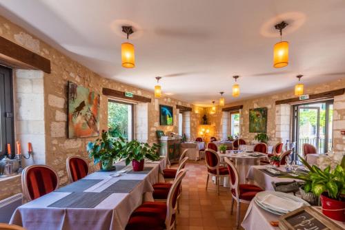 um restaurante com mesas, cadeiras e janelas em Moulin de Vigonac em Brantôme