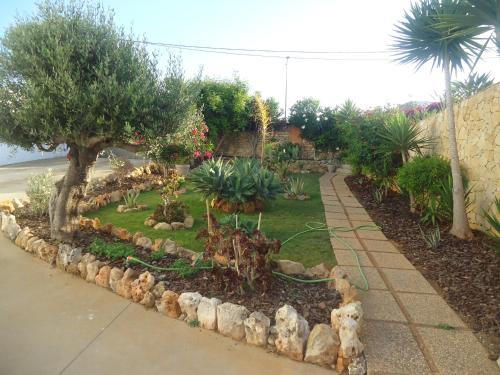 einen Garten mit Bäumen und Pflanzen und einen Bürgersteig in der Unterkunft VIVENDA L'OLIVIER in Quarteira
