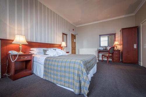 
a hotel room with a bed, chair, and nightstand at The Royal Hotel in Oban
