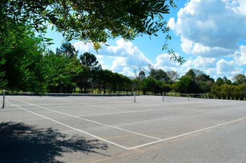 a tennis court with trees in the background at Argentino Hotel Casino & Resort in Piriápolis
