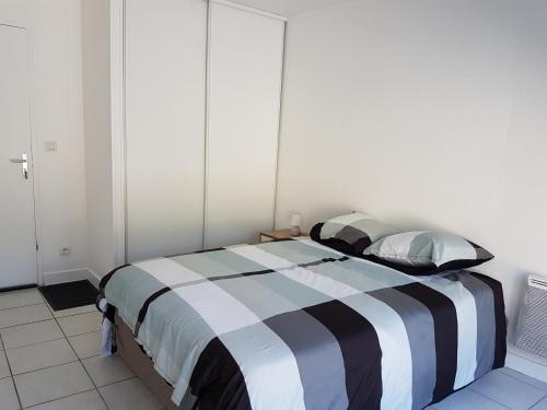 ラ・ロシェルにあるStudio proche Île de Réのベッドルーム1室(黒と白のストライプの掛け布団付きのベッド1台付)