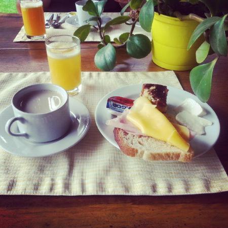 een bord eten met een broodje en een kop koffie bij Casa Bossa Nova Guesthouse in Ubatuba