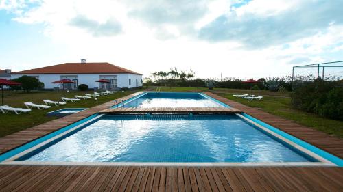 a large swimming pool with chairs and a house at Hotel Santa Maria in Vila do Porto