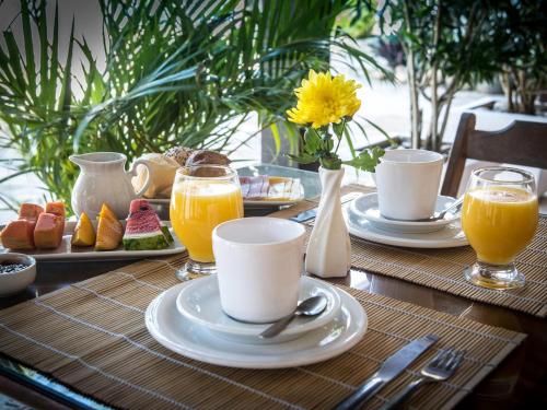 ein Tisch mit Tellern voller Essen und Gläsern mit Orangensaft in der Unterkunft Pousada Kairos & Spa em Búzios in Búzios