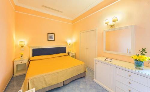 a bedroom with a bed and a dresser and a mirror at Hotel Iaccarino in SantʼAgata sui Due Golfi