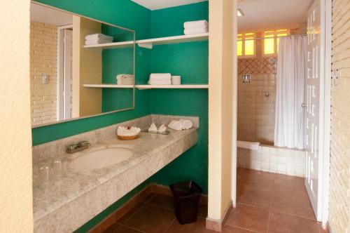 a bathroom with a sink and a green wall at Real Bananas All Inclusive in Acapulco