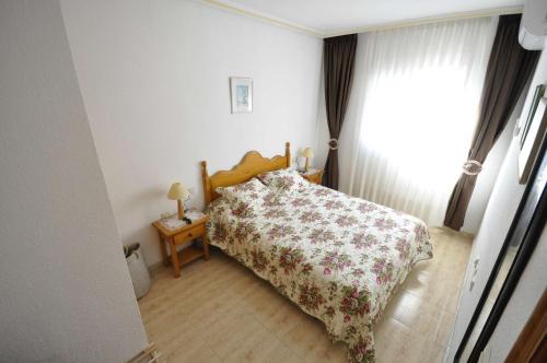 トレビエハにあるBergantin Fantastic sunny apartmentのベッドルーム1室(花柄のベッドカバー、窓付)