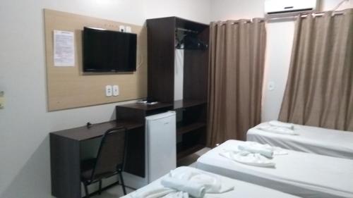 a hotel room with two beds and a television at Entre Rios Hotel in Picos