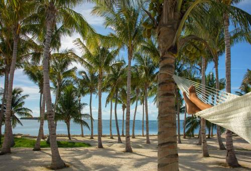 a person laying in a hammock on a beach at Bungalows Key Largo - All Inclusive in Key Largo