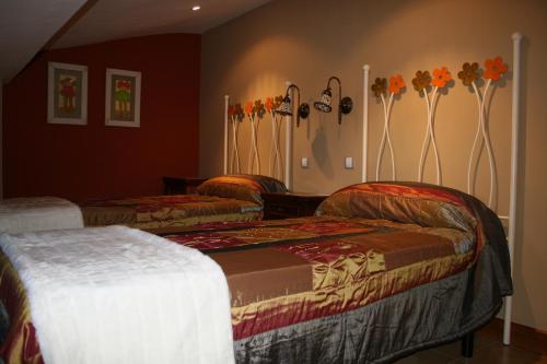 two beds in a room with flowers on the wall at Las Casitas de Papel in Ampudia