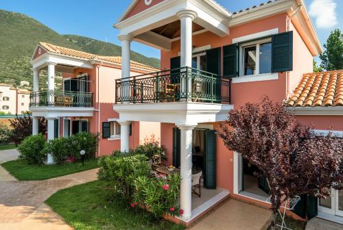a large pink house with a balcony at Aktes villas in Vasiliki