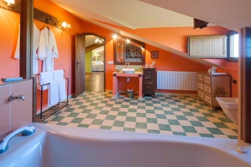 ein orangefarbenes Badezimmer mit einer Badewanne und einem karierten Boden in der Unterkunft Posada Real Ruralmusical in Puerto de Béjar