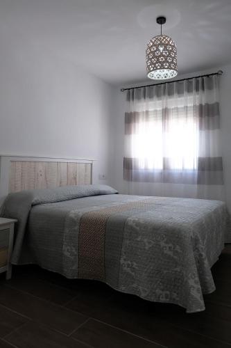 a bedroom with a bed and a window and a chandelier at El Ventanal de Almagro in Almagro