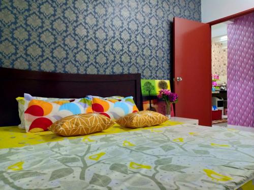 ein Schlafzimmer mit einem Bett mit bunten Kissen in der Unterkunft Casa Inderaloka Pantai Batu Buruk in Kuala Terengganu