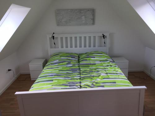 a white bed with a green comforter in a room at Mariazeller Rooms in Mariazell