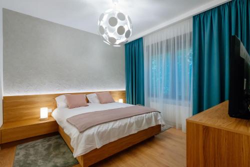 a bedroom with a bed with blue curtains and a television at Arbans Elegant apartment in the city center in Bucharest
