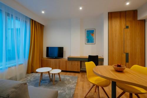 ein Wohnzimmer mit einem Tisch und gelben Stühlen in der Unterkunft Arbans Elegant apartment in the city center in Bukarest