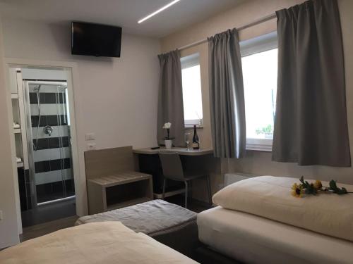 a bedroom with two beds and a desk and a window at Garni San Paolo in Appiano sulla Strada del Vino
