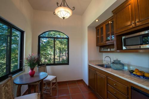 a kitchen with a table and a sink and windows at Hacienda Todos Los Santos in Todos Santos