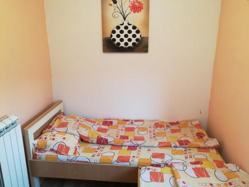 a bed with a quilt and a picture on the wall at SAŠA in Kolašin