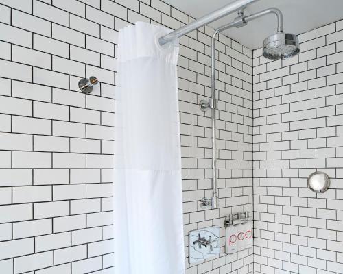 ducha de azulejos blancos con cortina de ducha en Pod 51, en Nueva York