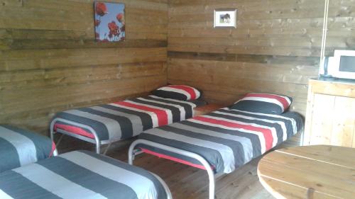 three beds in a room with wooden walls and a table at blokhut us Mem in Boazum