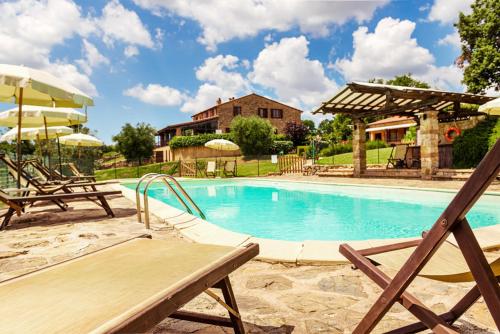 Ribolla的住宿－Agriturismo & Cantina Tenuta Casteani，一个带椅子和遮阳伞的游泳池以及一座房子