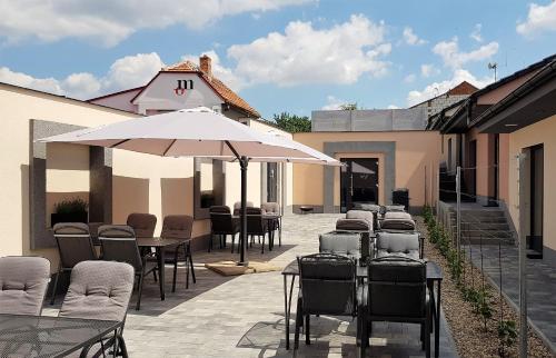 a row of tables and chairs with an umbrella at Penzion U Křížku in Kobylí