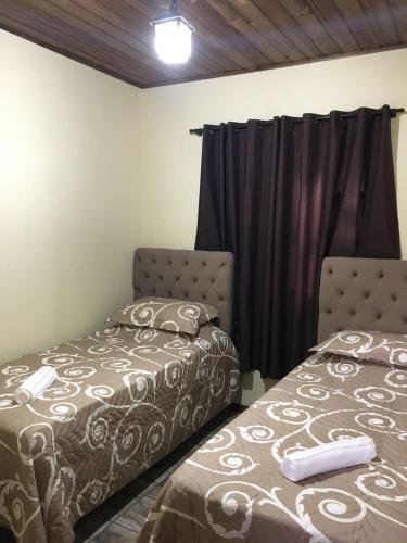 a bedroom with two beds and a window at Hotel Praia Do Rosa in Praia do Rosa
