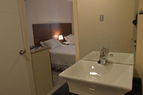 a bathroom with a sink and a bedroom with a bed at Origen Apart-Hotel in Santiago