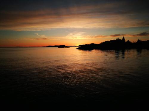 a sunset over a body of water with an island at Kuvågen 23 in Vågenes