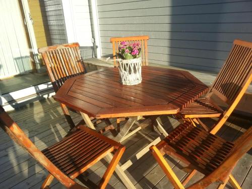 a wooden table with two chairs and a vase of flowers at Kuvågen 23 in Vågenes