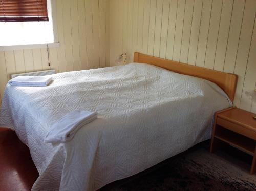 a bedroom with a white bed with a wooden headboard at Fraendgardur in Hofsós