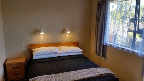 a small bedroom with a bed with a window at Moeraki Boulders Motel in Hampden