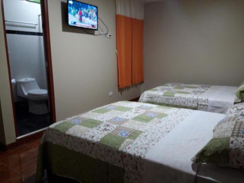 a bedroom with two beds and a tv on the wall at Gran Hotel Virrey in San Ramón