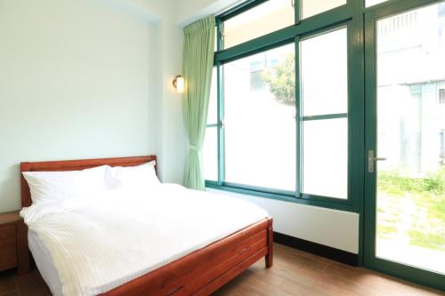 a bedroom with a bed and a large window at Rgb-光與影的民宿 in Hualien City